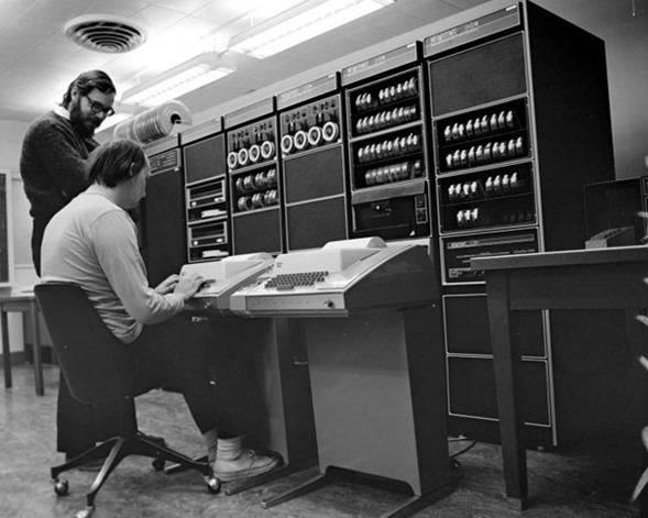 Dennis Ritchie (standing) and Ken Thompson with a PDP-11, circa 1972